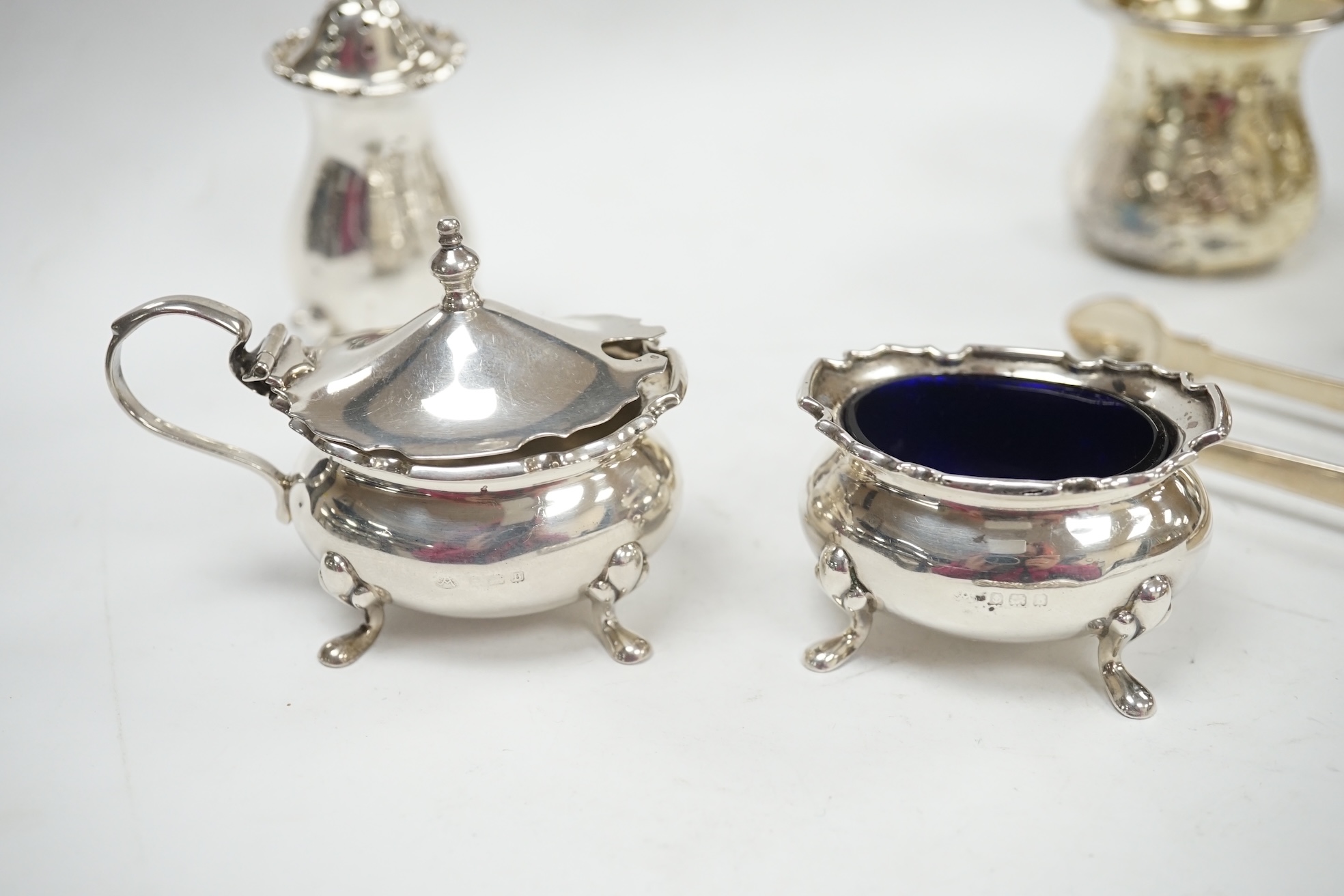 A George V silver four piece condiment set by Adie Bros. Birmingham, 1926 and three other items including a pair of Georgian silver sugar tongs, London 1799. Condition - poor to fair